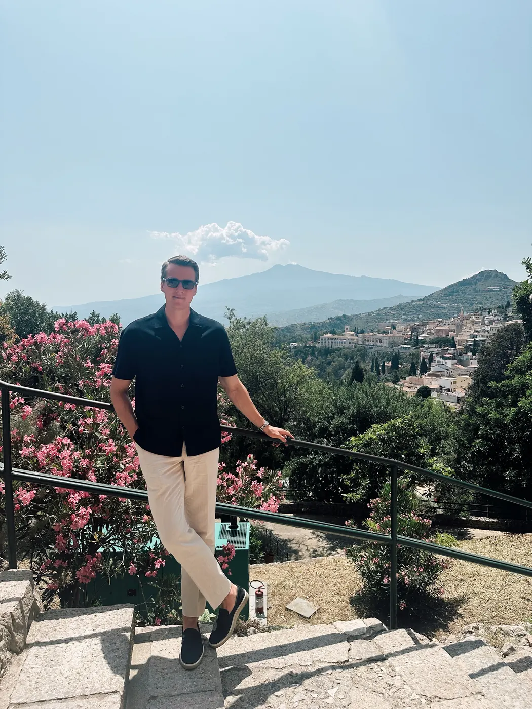 Kevin on a terrace above a hillside town, with mountains behind